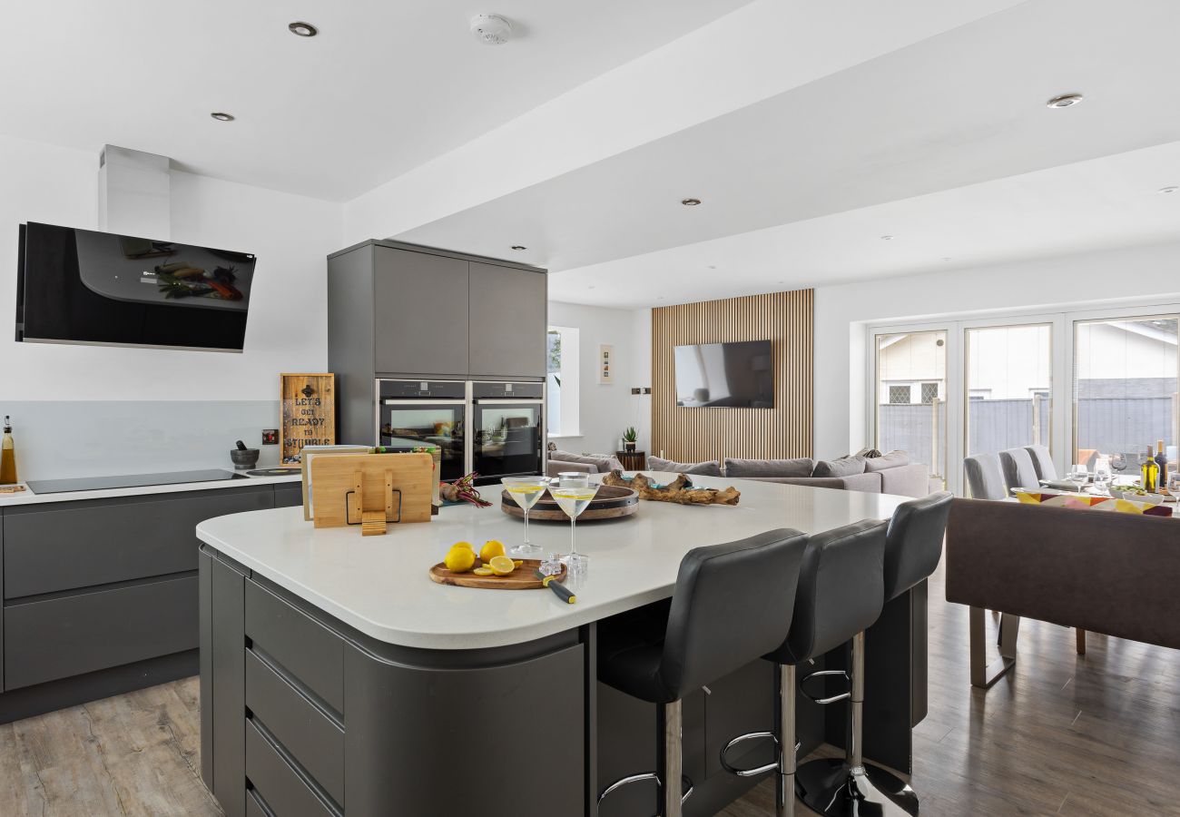 Contemporary kitchen with quartz countertops, island seating, and high-end appliances in a holiday rental near Teignmouth.